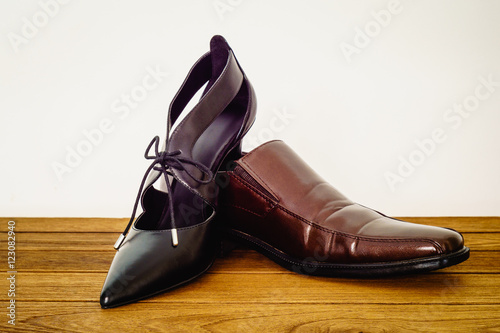 man shoes and woman black high heels shoes on brown wooden backg