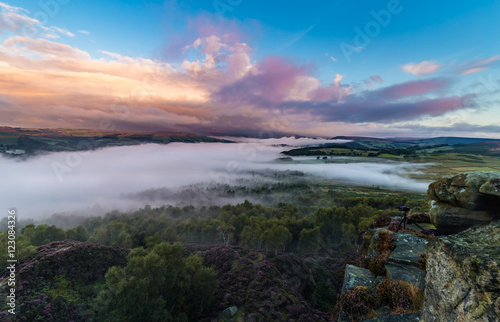 Colorful Surise Clouds over Valley Covered in Mist with Photography Camera on the Edge of Rocks