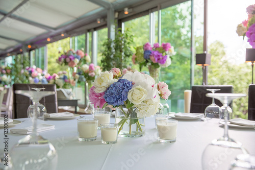 Tender bouquets stand between white candles on the dinner tables