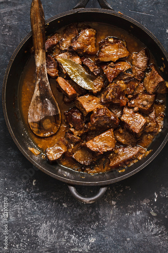Braised beef stew in a pot. Stewed meat casserole. Top view.
