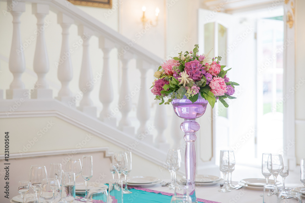 Pink and violet bouquet stands in a high vase on round dinner ta Pink and violet bouquet stands in a high vase on round dinner ta