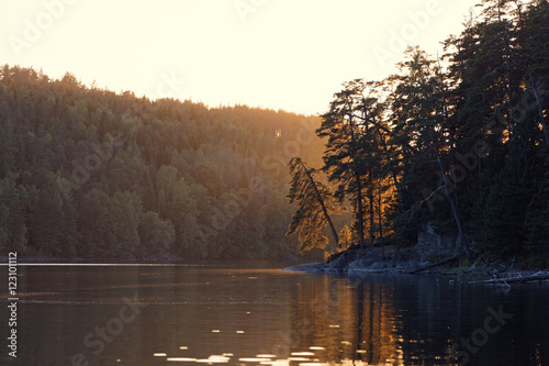 Sunset over the Olhava lake in Finland with backlit pine trees