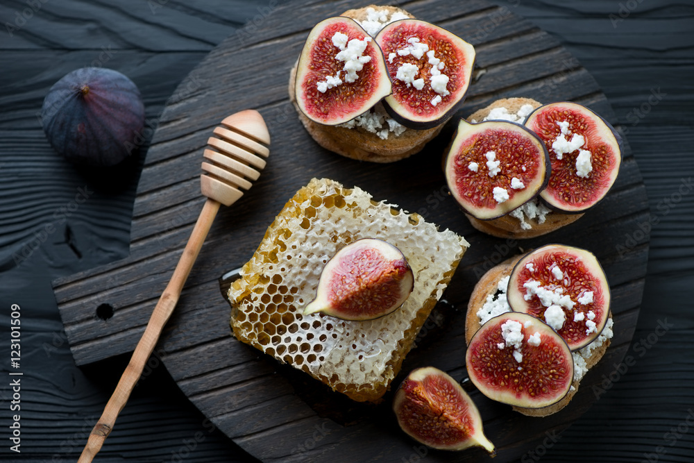 Bruschetta with figs and honey on a dark wooden serving board
