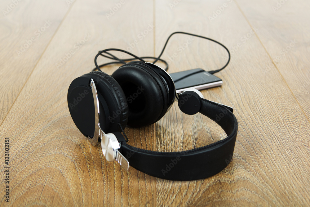 Headphones and phone on a wooden surface Headphones and phone on a wooden surface