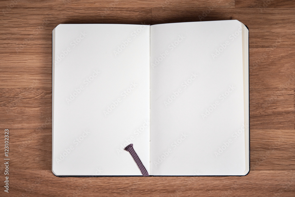 White pages of open notebook on a brown wooden table White pages of open notebook on a brown wooden table