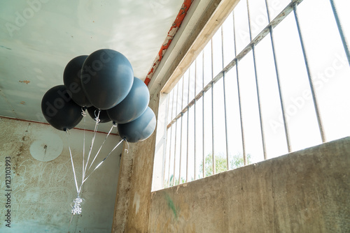 Black balloon inside a deserted room with windows in the background