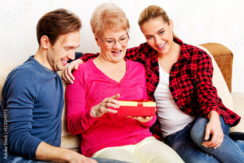 Happy family - couple with old woman who holding gift box photo