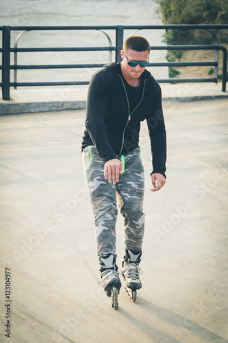 young man with inline skates ride in summer park seafront outdoor rollerskater photo