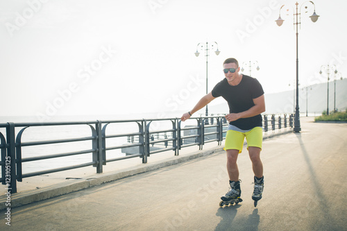 young man with inline skates ride in summer park seafront outdoor rollerskater