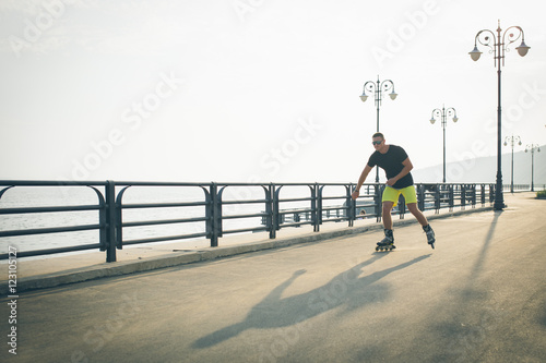 young man with inline skates ride in summer park seafront outdoor rollerskater