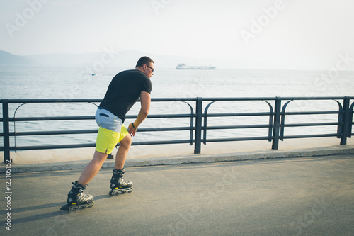 young man with inline skates ride in summer park seafront outdoor rollerskater photo