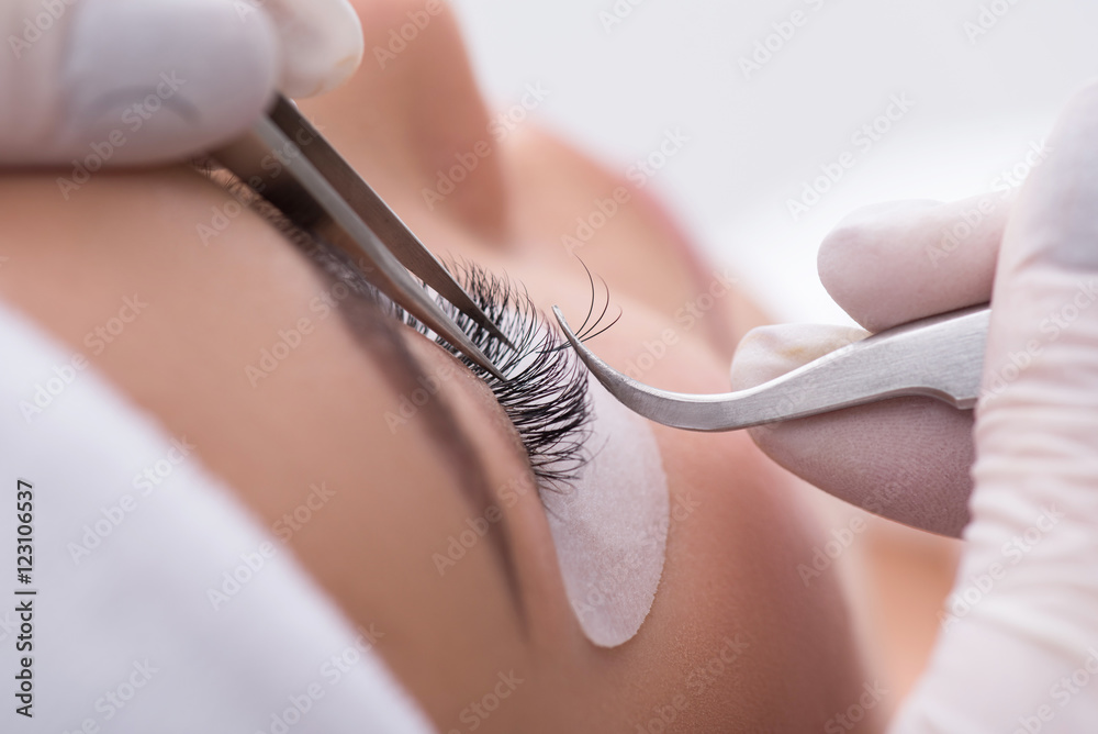 Skillful cosmetologist undergoing lash extension procedure - obrazy, fototapety, plakaty 
