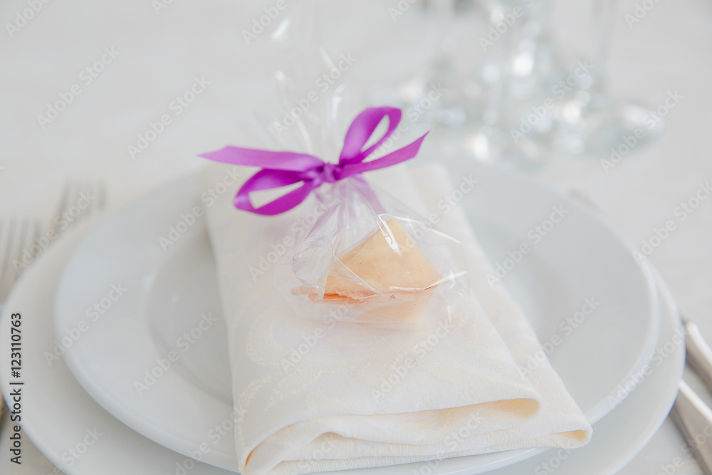 Sweets in a packet with violet ribbon stand on the crockery serv Sweets in a packet with violet ribbon stand on the crockery serv
