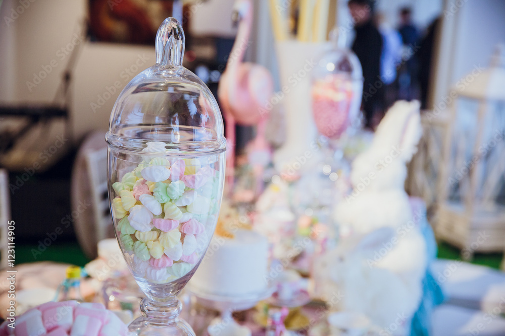 Different colored marshmallows lie in a glass bottle on the tabl Different colored marshmallows lie in a glass bottle on the tabl