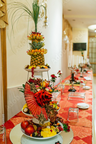 Red fan and paper roses decorate a stand with exotic fruits