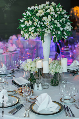 White festive served dinner table decorated with white bouquet o