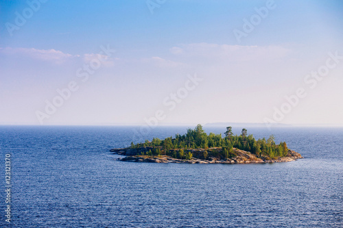 Typical landscape in Karelia - blue sky, clouds, big lake and a lot of distant green islands, trees, stones and rocks