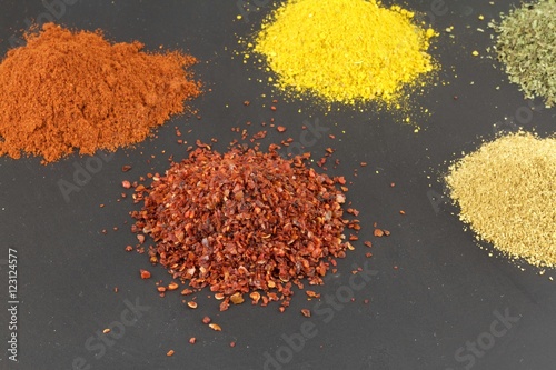 Various spices , red pepper flakes, grounded red pepper, curry, milled cummin and dried mint.