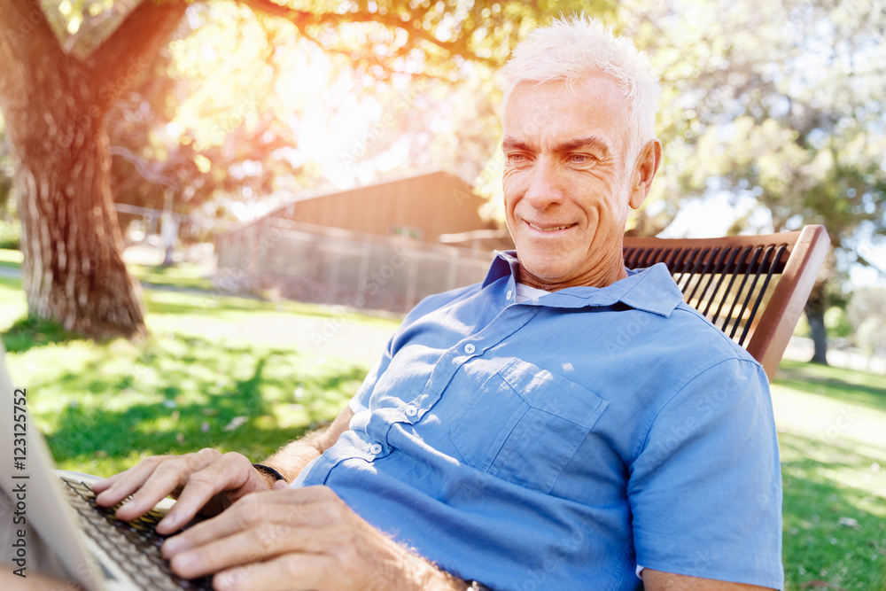 Senior man with notebook sitting in the park Senior man with notebook sitting in the park