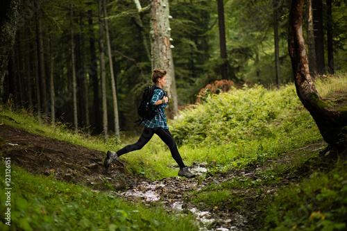 adventurous woman jumps over a water in a forest photo