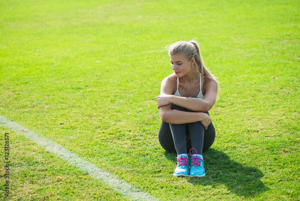 A young girl is doing exercises and rests at the stadium