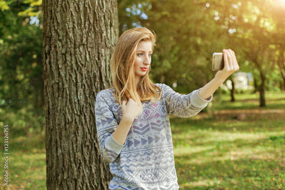 Beautiful girl with blue eyes makes selfie outdoors next to the tree and the house Beautiful girl with blue eyes makes selfie outdoors next to the tree and the house