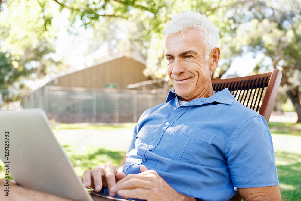 Senior man with notebook sitting in the park Senior man with notebook sitting in the park