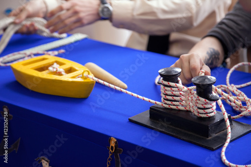 Kids learning to moor on toy ship model at sailing school