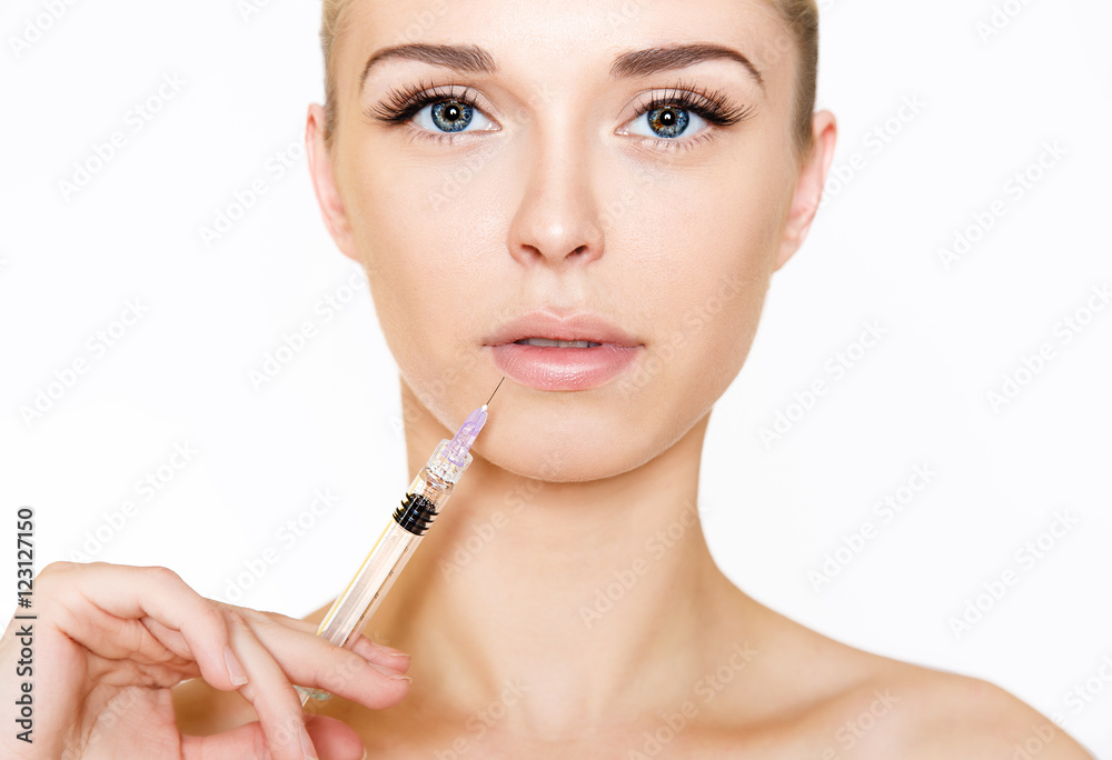 Beautiful young woman gets beauty injection in lips. Isolated over white background Beautiful young woman gets beauty injection in lips. Isolated over white background