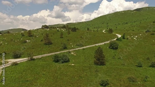 Camera flying around beautiful green grassy landscape surrounded by mountains photo