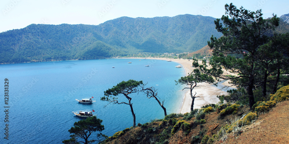 Obraz premium Tourist boats in the sea. View on Adrasan Bay. Aged photo. Pine trees and sea. Toned image. Walking the Turkey's Lycian Way. Antalya Province, Turkey. Wide format for a slider.