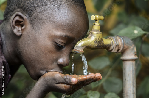 Foto Little African Boy Drinking Healthy Clean Water from Tap