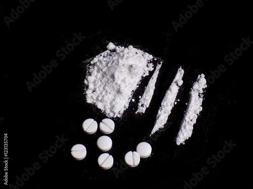 Cocaine drug powder pile and lines, pills on black background