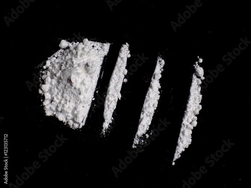 Cocaine drug powder pile and lines on black background