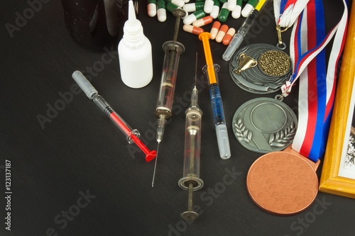 Doping in sport. Abuse of anabolic steroids for sports. Anabolic steroids spilled on a wooden table. Fraud in sports. Pharmaceutical industry. False victory.
