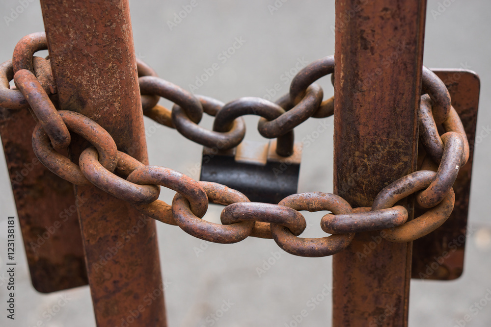 closeup shot of a big metallic chains with big lock that locks gates closeup shot of a big metallic chains with big lock that locks gates