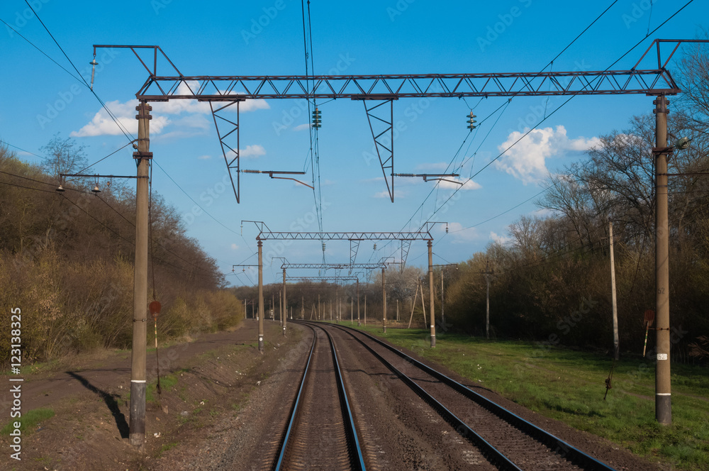 a view of a few curved railroad tracks from the last car with blue sky as background