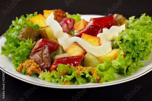 Salad.Chorizo sausage, lettuce, pickled cucumber fried potato with mayonnaise.Dark background