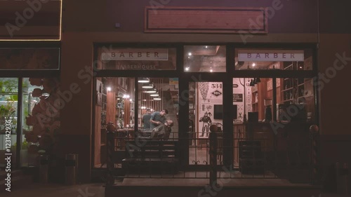 Vintage barbershop exterior HD video. Barber working with client beard. View from street through panoramic glass window entrance to retro hairdressing salon interior