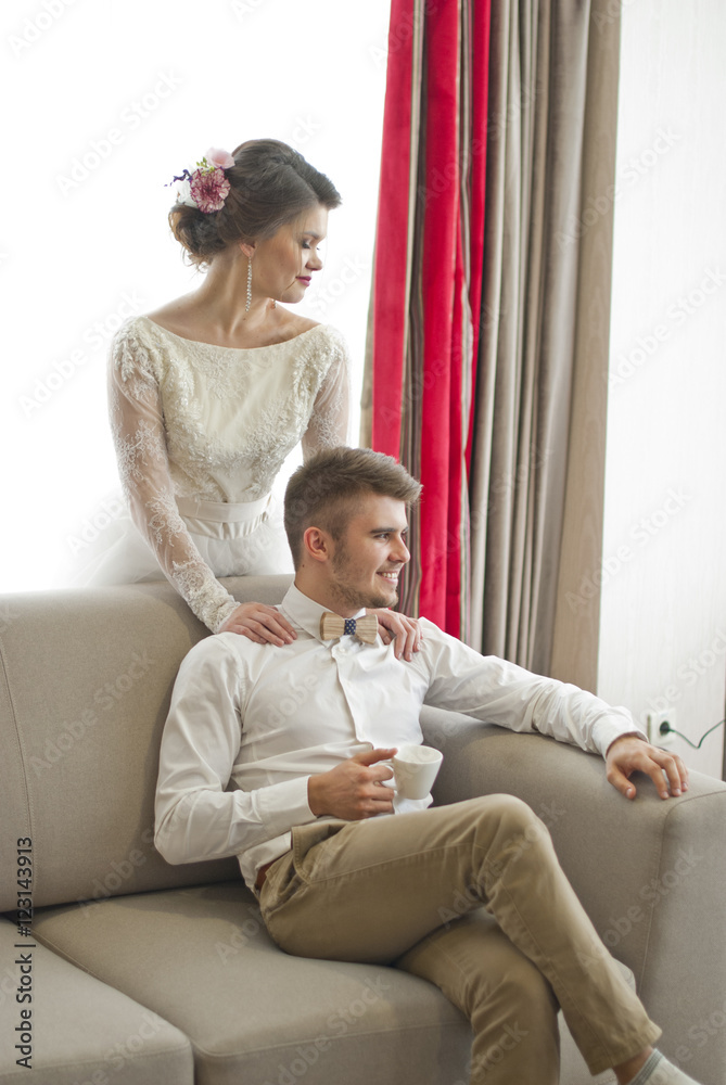 Wedding couple in love. Beautiful bride in white dress with handsome groom. Bright interior with big window. 