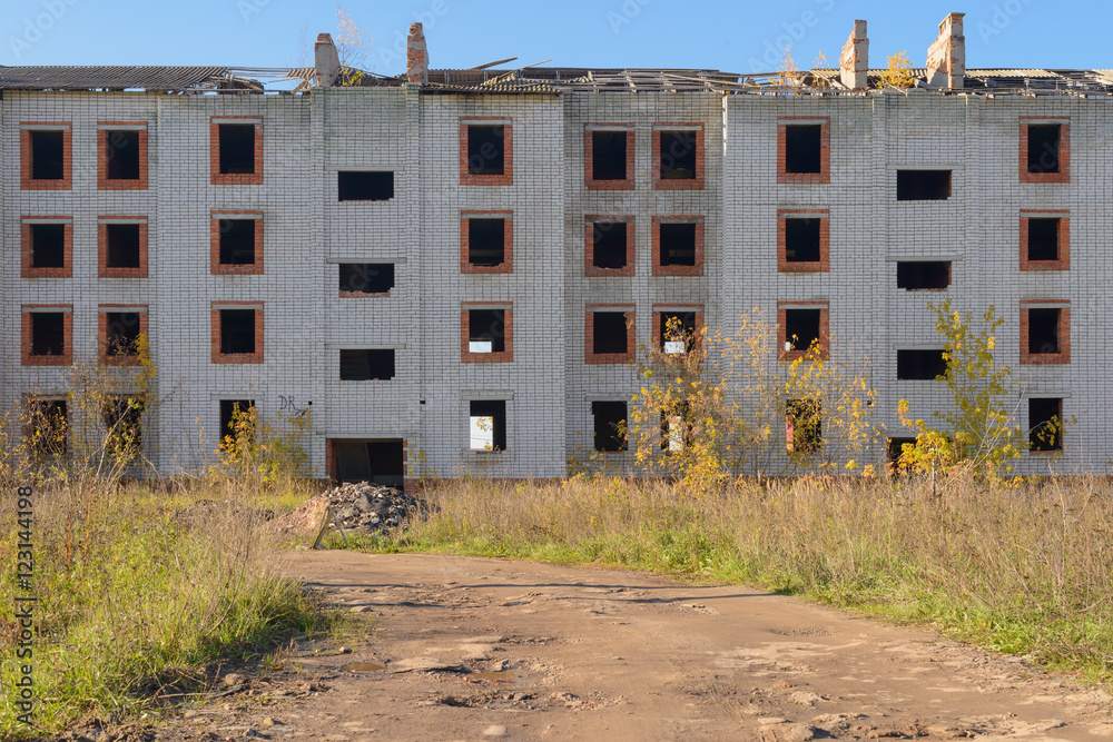 dilapidated abandoned brick apartment house among the fields