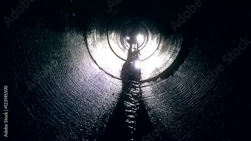 Pair of man looking for orienteering competition check point in dark tunnel.