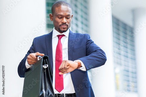 Successful black businessman looking at his watch outdoor