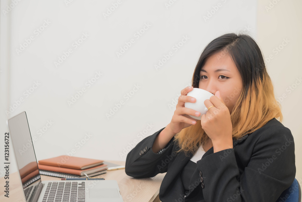 Businesswoman drinking coffee working on his laptop on the desk Businesswoman drinking coffee working on his laptop on the desk