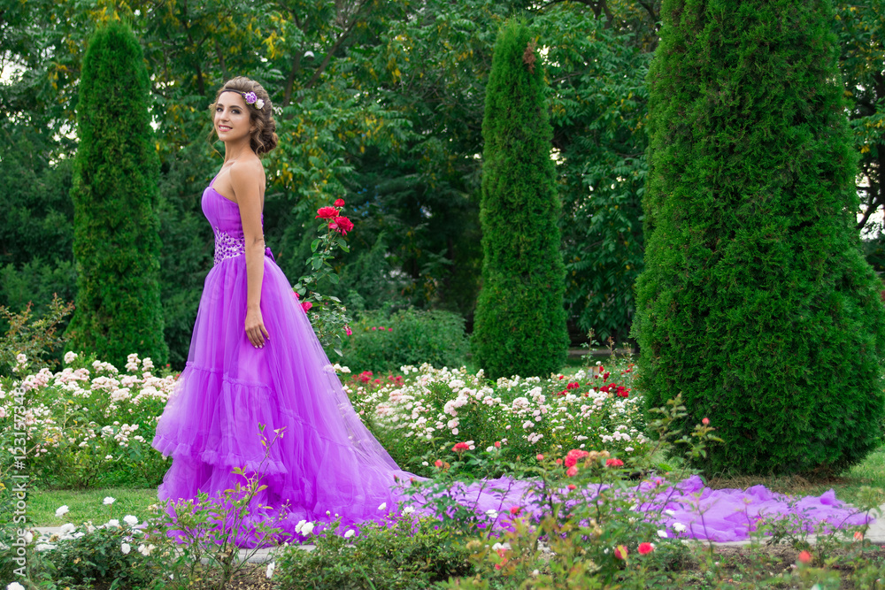 Beautiful girl in violet dress among in the garden