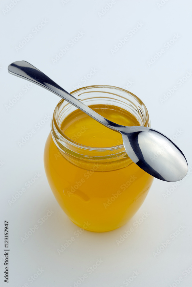 Honey in glass jar with spoon on top. Honey in glass jar with spoon on top.