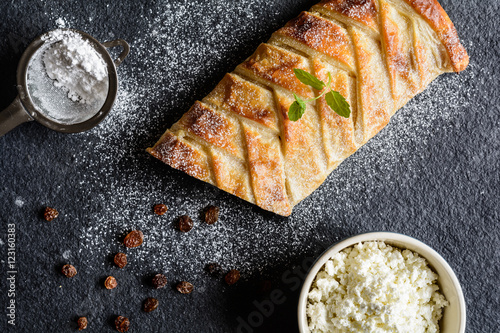 Cuadro en lienzo Braided strudel stuffed with curd and raisins, sprinkled with icing sugar