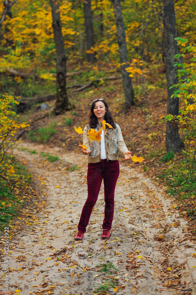 happy woman toss up autumn leaves