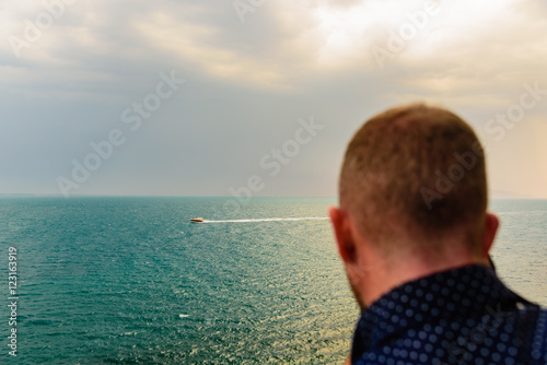 A man watching the sea and a boat at the horizon