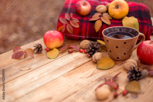 Autumn composition on a wooden background. Still life, food and drink, apples, pumpkin, nuts, cone, tea.